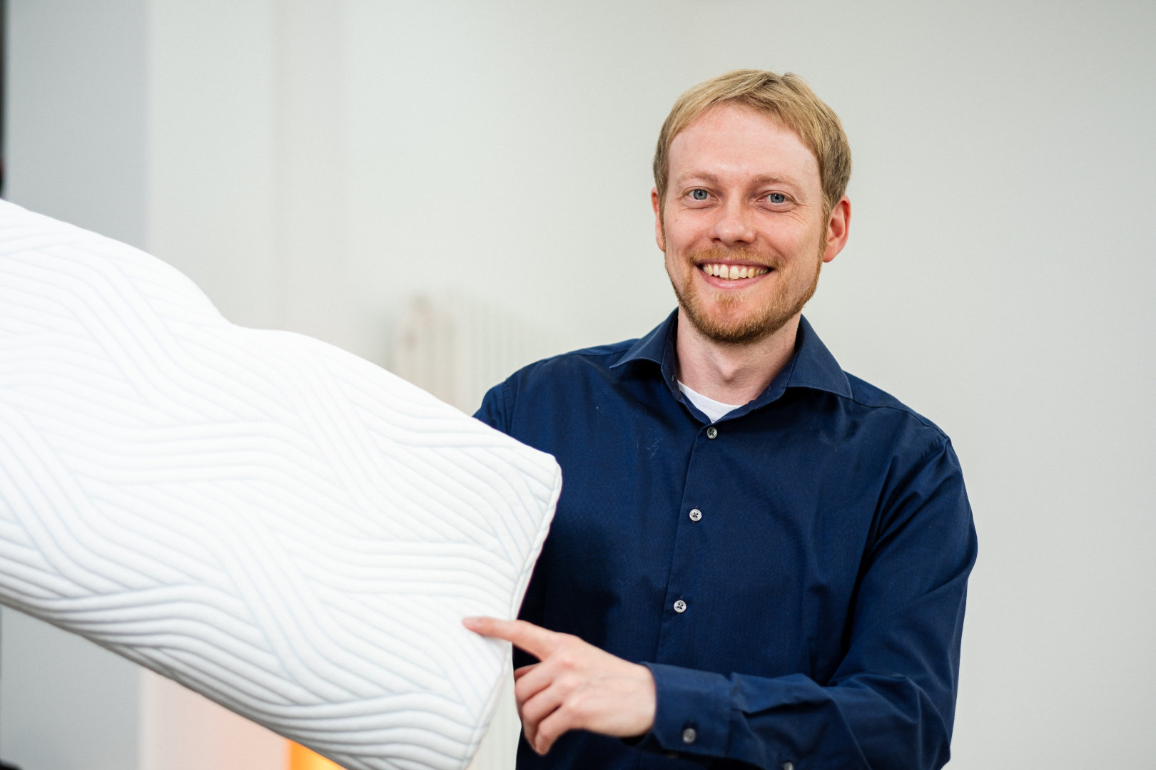 Berater von Betten VIKINGS hält ein ergonomisches Kopfkissen für die Schlafberatung