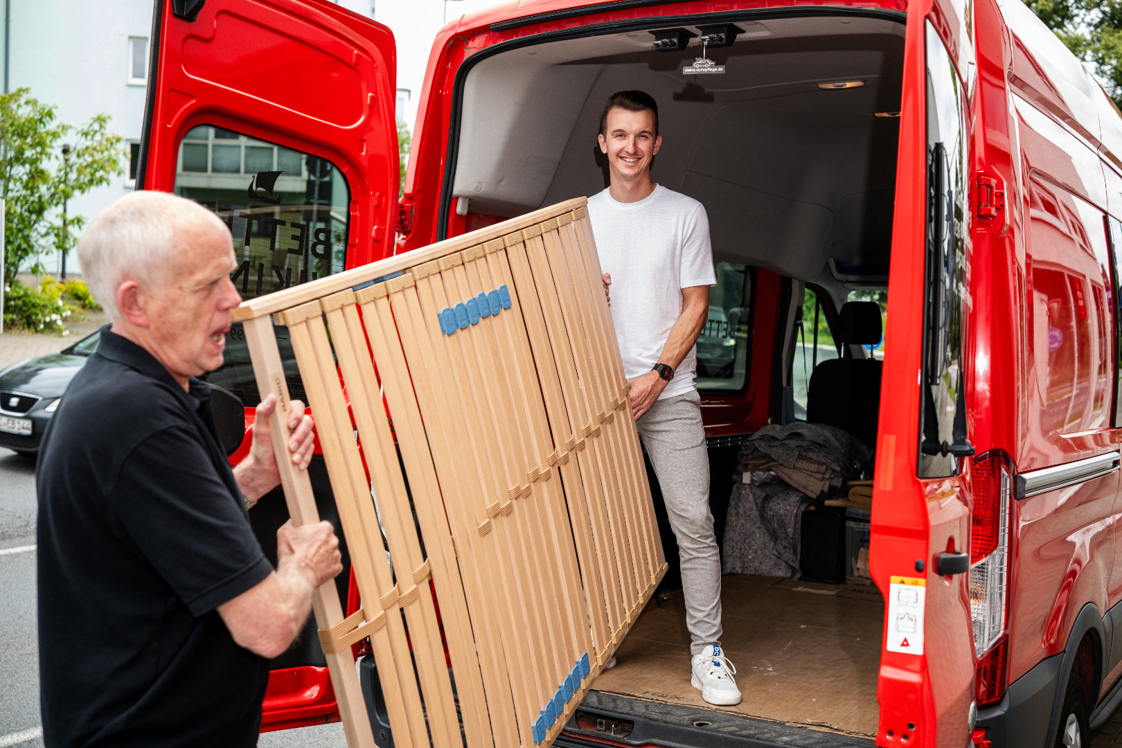 Das Betten VIKINGS Team liefert einen Lattenrost mit dem roten Firmenfahrzeug aus