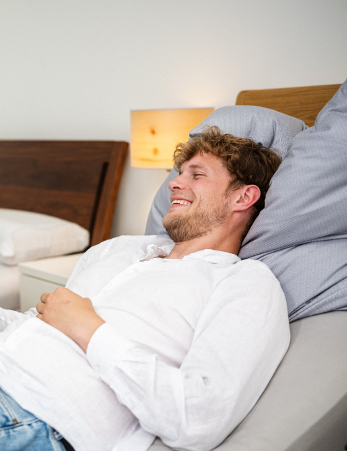 Mann testet entspannt ein Komfortbett bei der Bettenberatung